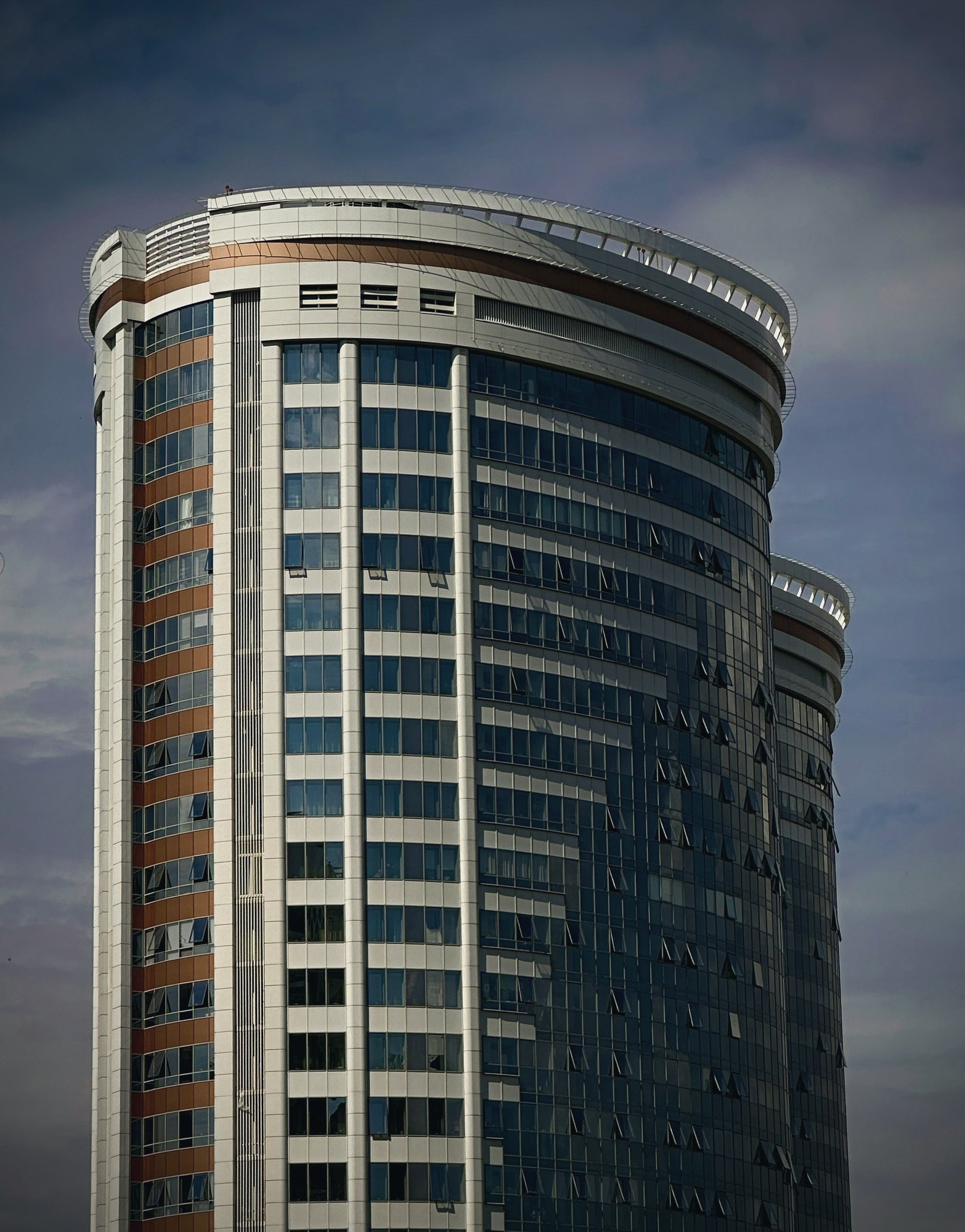 Curved glass high-rise tower against an evening sky