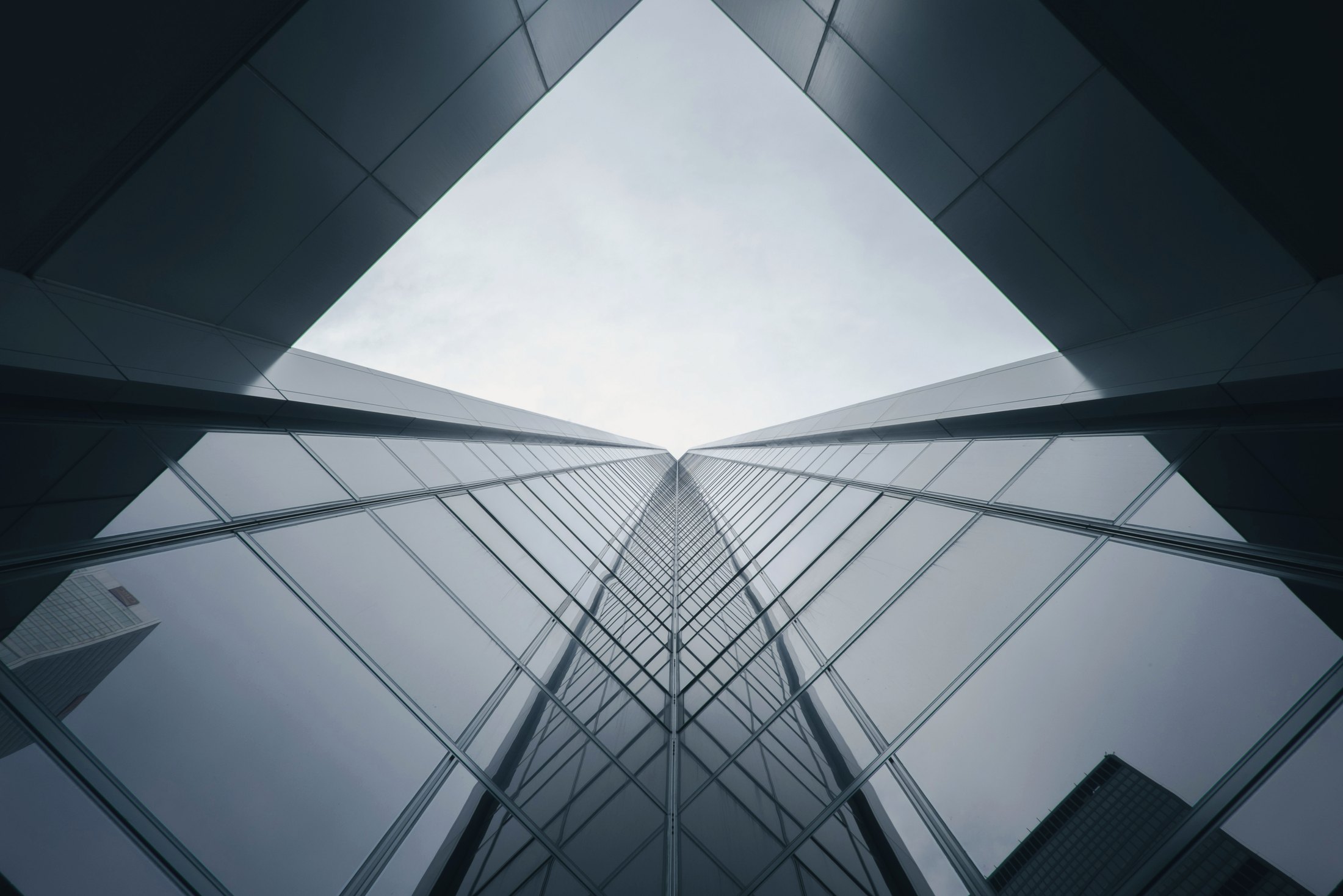 Looking up between two mirrored glass towers toward the sky